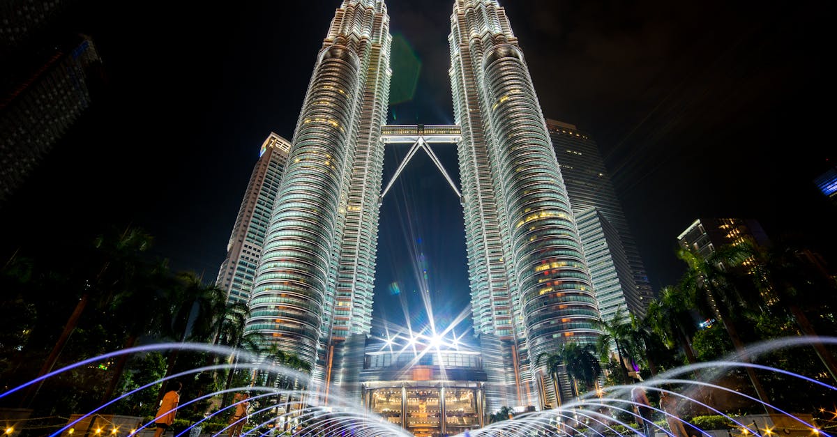 Stunning night view of the illuminated Petronas Twin Towers in Kuala Lumpur with fountains in the foreground.