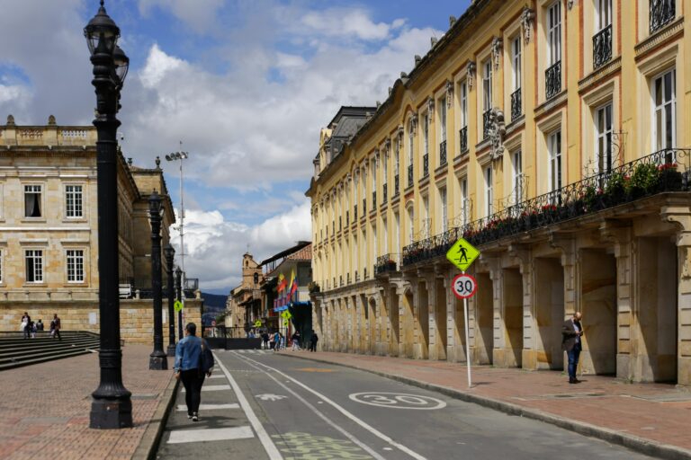 A vibrant day on a historic street in Bogotá, showcasing colonial architecture.