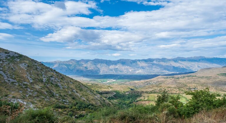 Breathtaking view of the Albanian countryside with mountains and lush valleys under a bright blue sky.