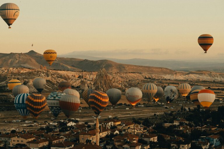 A breathtaking view of colorful hot air balloons soaring over Cappadocia's unique landscape during sunrise.
