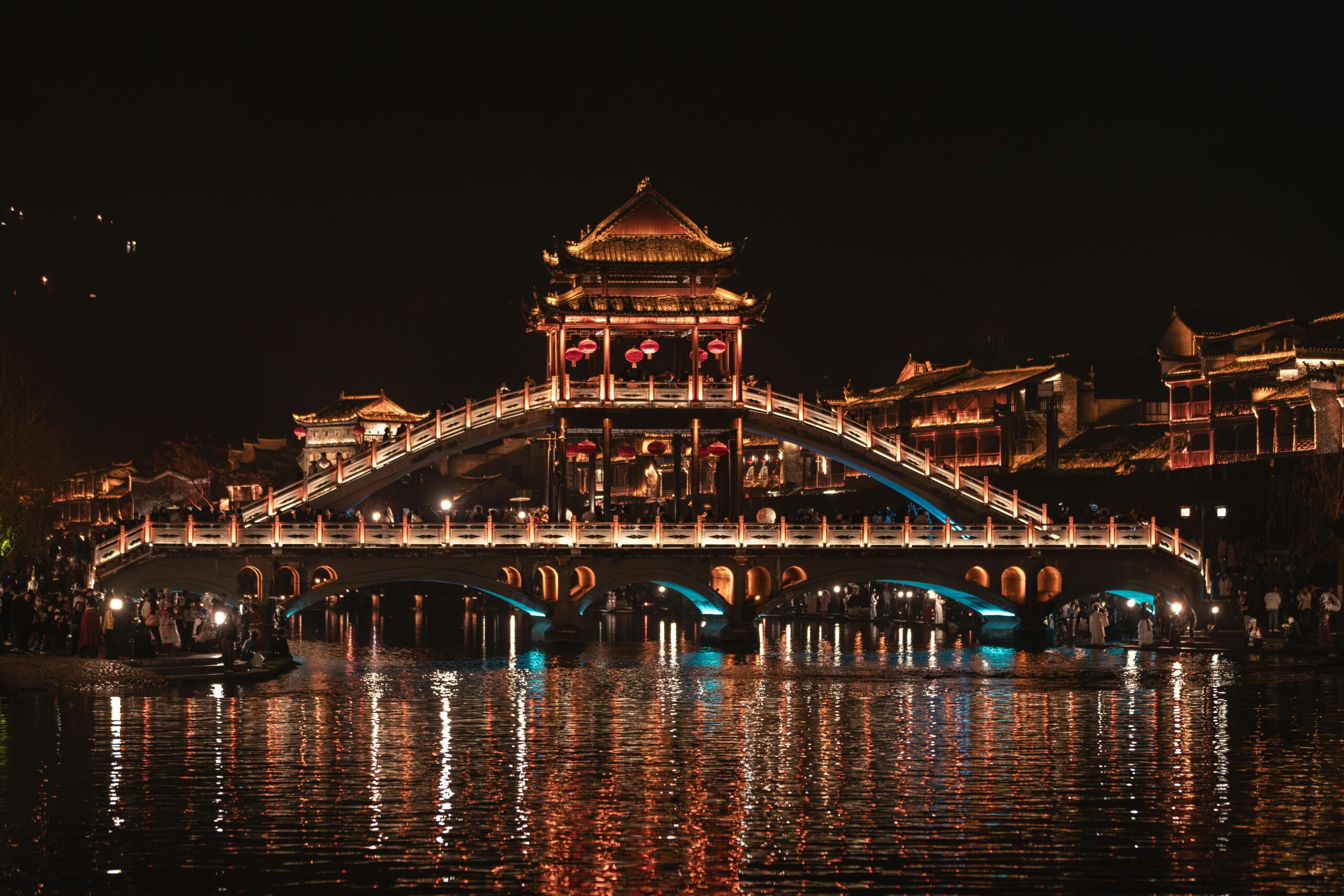 Stunning view of the illuminated Fenghuang Bridge in Xiang Xi, China at night, reflecting on the serene river.