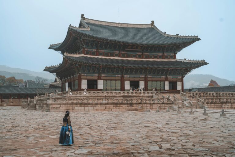 Woman in traditional hanbok attire walking past Seoul's iconic Gyeongbokgung Palace.