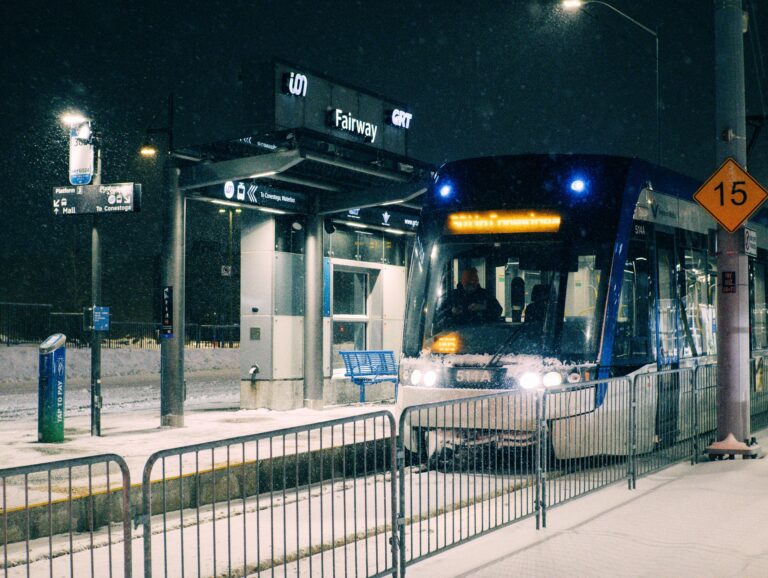 A snowy night at Fairway Station in Kitchener, Ontario with a light rail transit arriving.