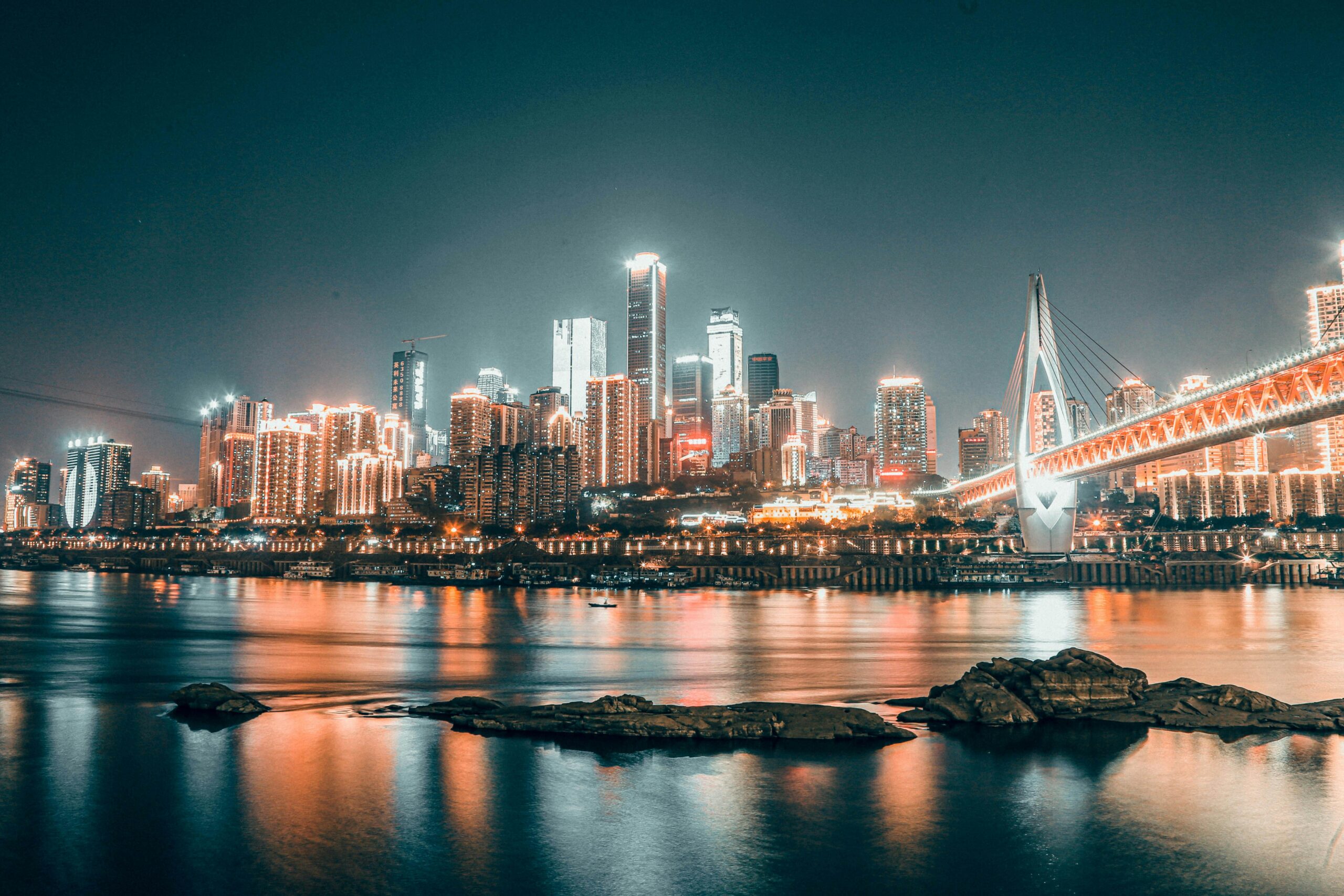 Stunning view of Chongqing city skyline at night with illuminated buildings and bridge reflections.