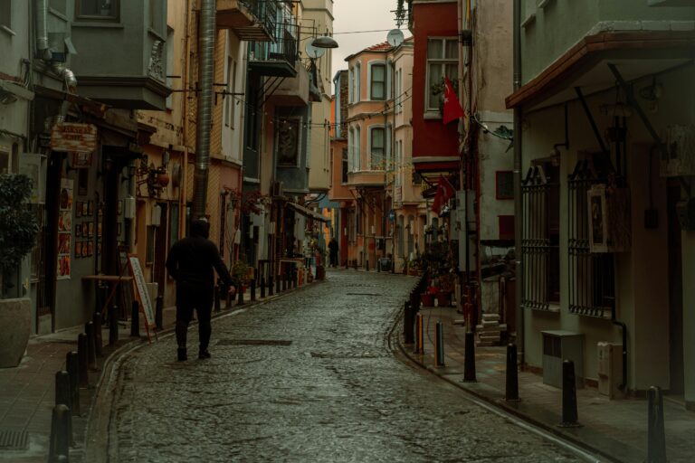 A person walks down a historic cobblestone street in Fatih, Istanbul, lined with colorful buildings.