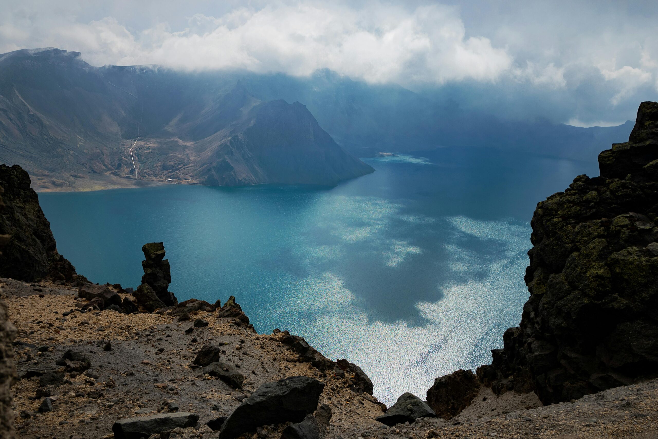 Breathtaking view of Heaven Lake surrounded by rugged mountains and clouds on Changbai Mountain, China.