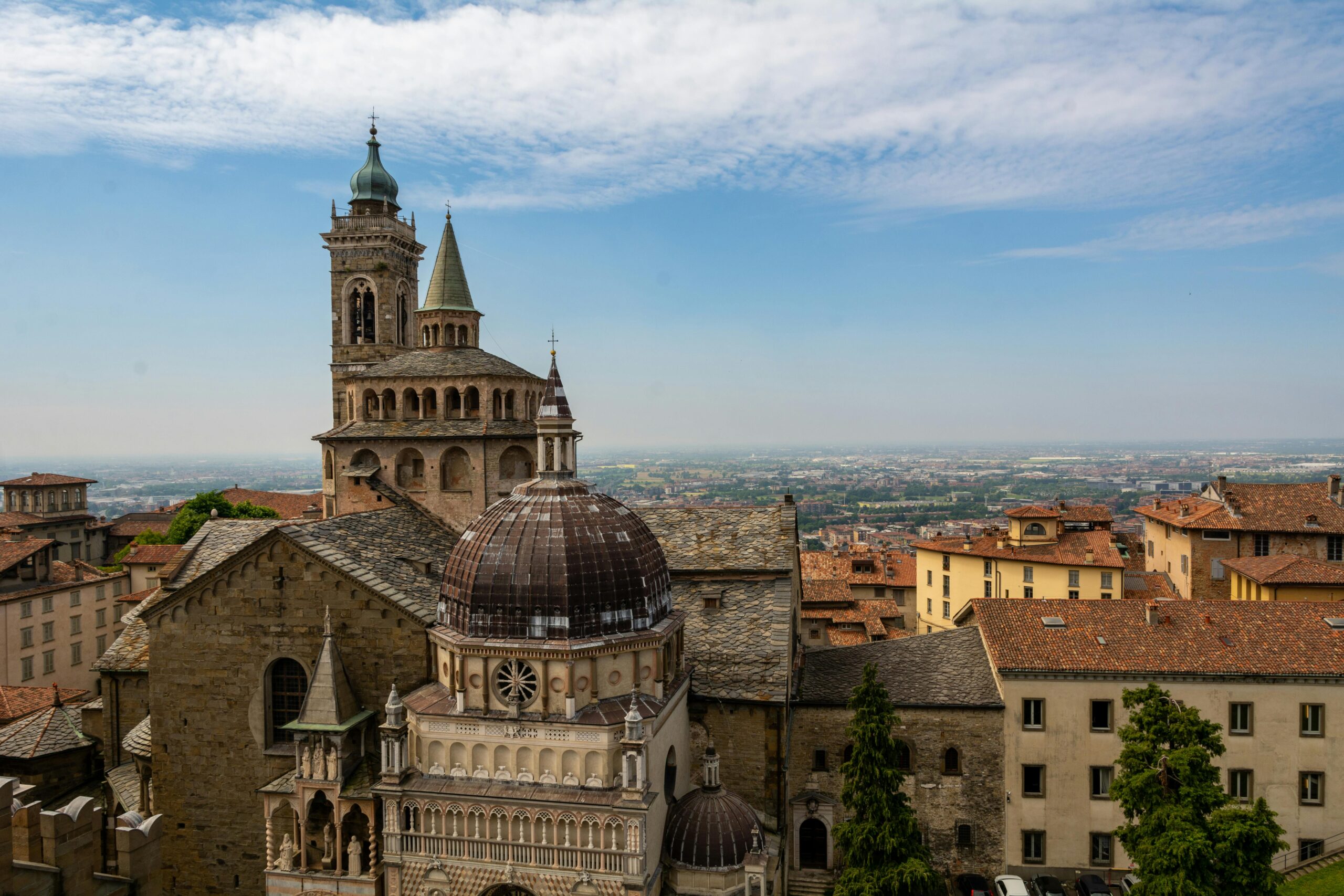 Aerial view of the historic Bergamo Cathedral in Italy under a bright blue sky.